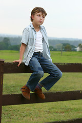 Image showing Country boy sitting on a fence