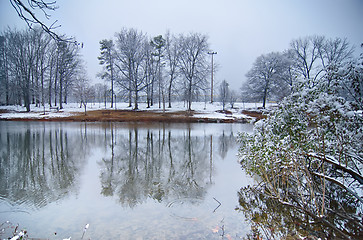 Image showing tree line reflections in lake during winter snow storm