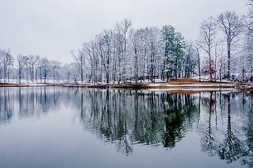 Image showing tree line reflections in lake during winter snow storm