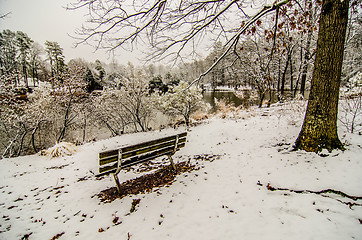 Image showing park bench in the snow covered park overlooking lake