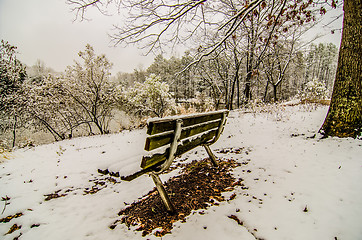 Image showing park bench in the snow covered park overlooking lake