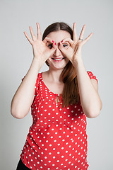 Image showing Smiling attractive woman looking through finger goggles