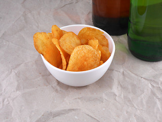 Image showing Beer bottle and potato chips on white plate