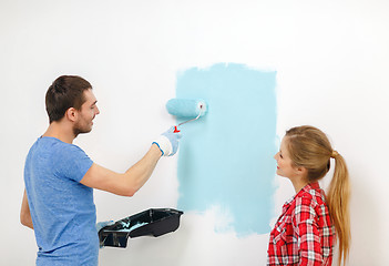 Image showing smiling couple painting wall at home