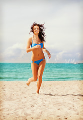 Image showing happy smiling woman jogging on the beach