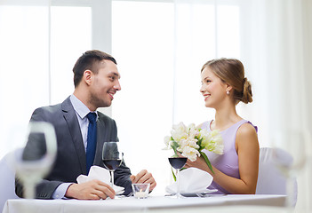 Image showing smiling man giving flower bouquet at restaurant