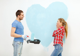 Image showing smiling couple painting big heart on wall