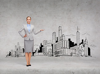 Image showing smiling young businesswoman showing town sketch