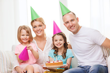 Image showing smiling family with two kids in hats with cake