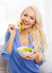 Image showing smiling young woman with green salad at home