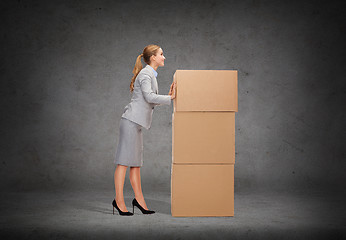 Image showing smiling businesswoman pushing tower of cardboards