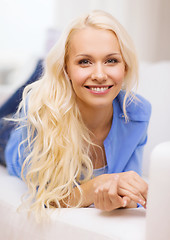 Image showing smiling young woman lying on sofa at home