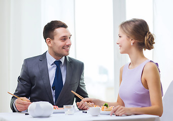 Image showing smiling couple eating sushi at restaurant