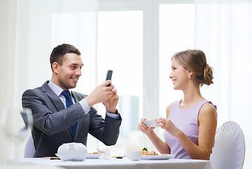 Image showing smiling couple with sushi and smartphones