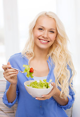 Image showing smiling young woman with green salad at home