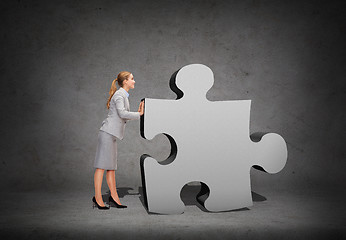 Image showing smiling businesswoman pushing big puzzle piece