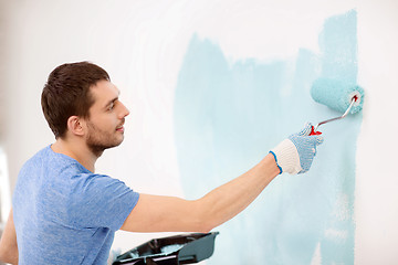 Image showing smiling man painting wall at home