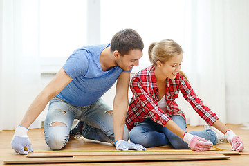 Image showing smiling couple measuring wood flooring