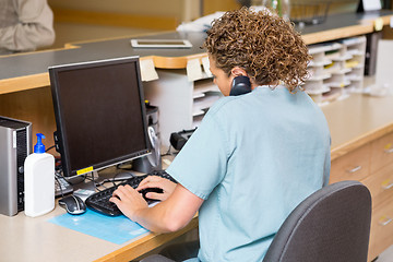 Image showing Nurse Answering Telephone While Working On Computer At Reception