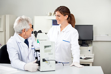 Image showing Scientist Discussing With Colleague While Using Microscope