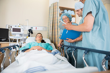 Image showing Nurses Discussing Patient's Report By Bed