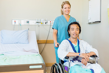 Image showing Mature Patient Sitting On Wheelchair While Nurse Assisting Him