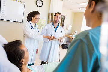 Image showing Happy Doctors Discussing Notes With Patient And Nurse In Foregro