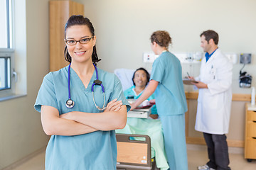 Image showing Confident Nurse Against Patient And Medical Team At Hospital