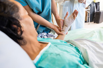 Image showing Nurse Putting Bandage On Patient's Hand While Standing By Doctor