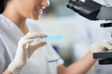 Image showing Researcher Holding Slide While Using Microscope