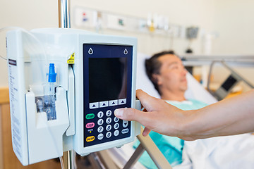 Image showing Nurse Operating IV Machine While Patient Lying On Bed