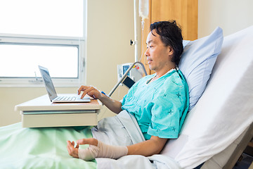 Image showing Patient With Crepe Bandage On Hand Using Laptop