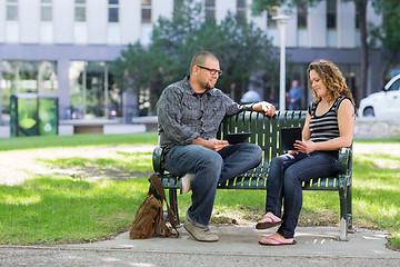 Image showing Students With Digital Tablets Sitting On Bench At Campus