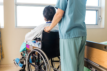 Image showing Nurse Holding Patient's Wheelchair's Handle By Window