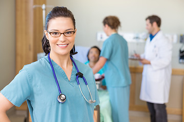 Image showing Nurse Smiling Against Patient And Medical Team In Hospital