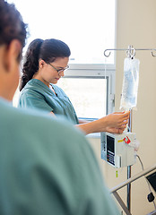 Image showing Nurse Adjusting IV Bag With Coworker In Foreground