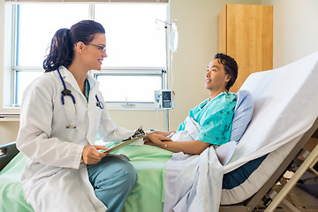 Image showing Doctor Consoling Male Patient Relaxing On Hospital Bed