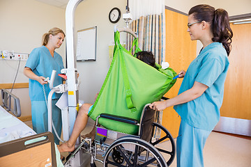 Image showing Nurses Transferring Patient From Hydraulic Lift To Wheelchair