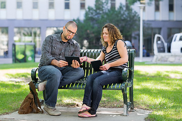 Image showing Students Using Digital Tablet On Bench At Campus