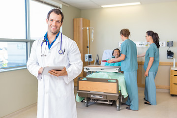 Image showing Doctor Using Tablet Computer With Nurses And Patient In Backgrou