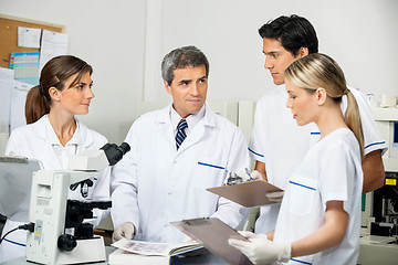 Image showing Scientist With Students Taking Notes In Laboratory