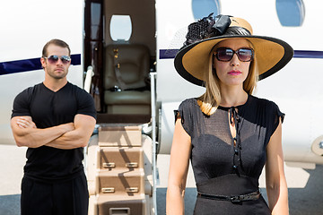 Image showing Beautiful Woman With Bodyguard Against Private Jet