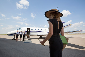 Image showing Woman Walking Towards Pilot And Stewardesses Against Private Jet