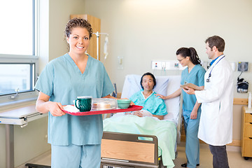 Image showing Nurse Holding Tray With Medical Team And Patient In Background