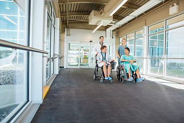 Image showing Medical Team Pushing Patients On Wheelchairs At Hospital Corrido