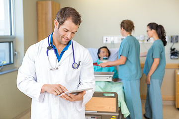 Image showing Doctor Using Digital Tablet While Nurses Serving Breakfast To Pa