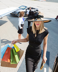 Image showing Rich Woman Carrying Shopping Bags While Boarding Private Jet