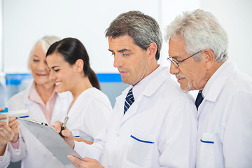 Image showing Researchers Discussing Over Clipboard