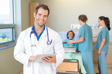 Image showing Doctor Using Tablet Computer While Nurses Serving Breakfast To P