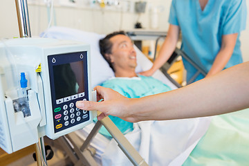 Image showing Nurse's Hand Operating IV Machine While Patient In Background